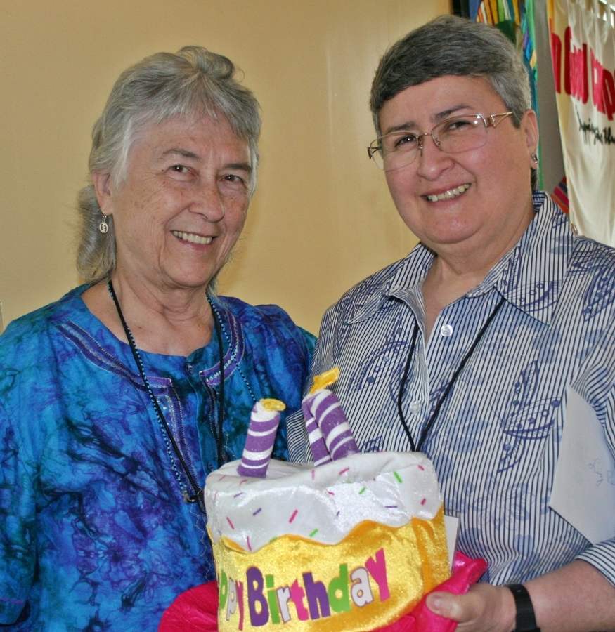 Mari Ego SL and Liz Deines SL pose for a photo holding a stuffed satin birthday cake.