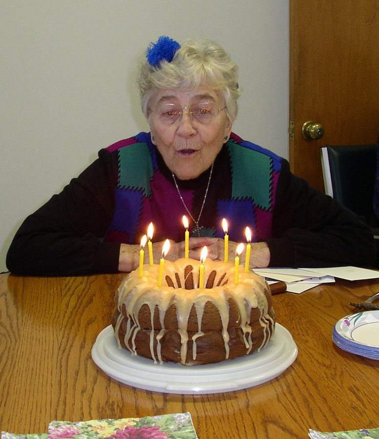 Lois Dunphy SL, with a party bow in her hair, blows out the candles on her birthday bundt cake.