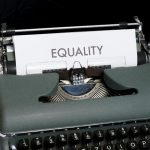 A closeup of an old typewriter with the word "equality" in large print on the paper coming out of the top.