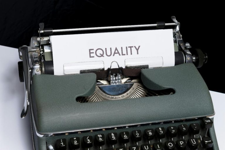 A closeup of an old typewriter with the word "equality" in large print on the paper coming out of the top.
