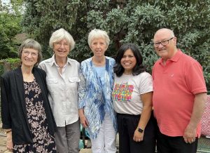 Five people pose together for a photo outside.
