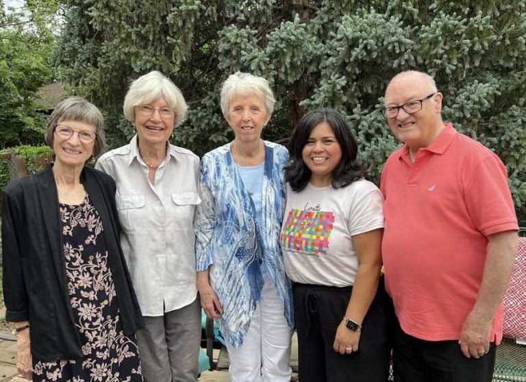 Five people pose together for a photo outside.