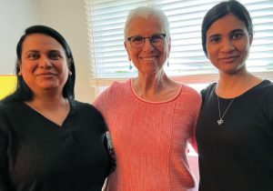 Three women pose together for a photo.