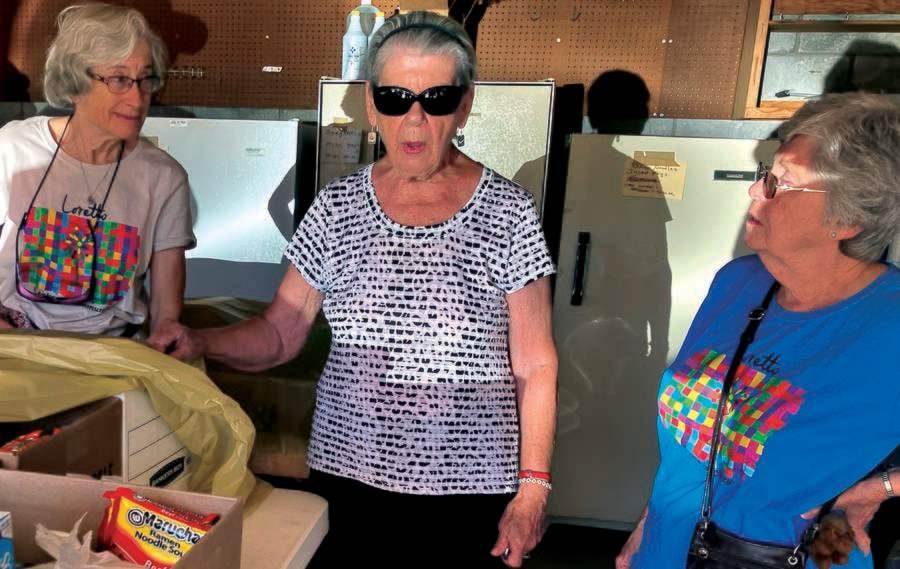 Three older women are pictured standing and talking as they volunteer with a food pantry in new Mexico.