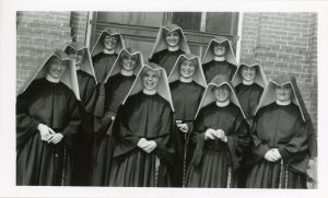 Archival photo of the 1949 Loretto Heights College reception class - eleven women in habits posing for a photo with joyous expressions on their faces.