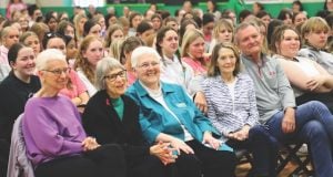 A photo of a school assembly with several Loretto members in the front row of chairs and rows of high school students behind them.