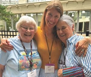 During a lunch break from a gathering, three women enjoy a hug and smile for the camera.