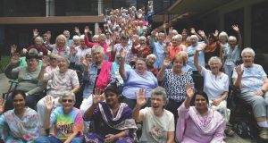 A group of about 100 women in a group drone picture giving an enthusiastic wave to the camera.