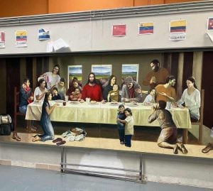 Photo of a mural depicting the Last Supper of Christ with migrants. Jesus sits in the center joined by Latinx people of varying ages.