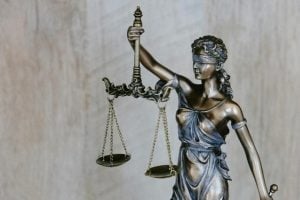 A bronze statue of lady justice wearing a blindfold and holding scales up.