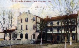 A vintage picture of a large white building with red roofs.