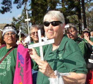 Women marching in protest carry white crosses with the names and ages of those who have died.