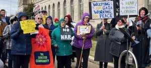 A group of protesters gather with signs on a cold day