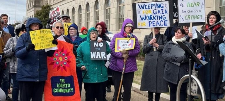 A group of protesters gather with signs on a cold day
