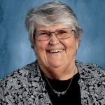 an older gray haired woman in professional attire smiles