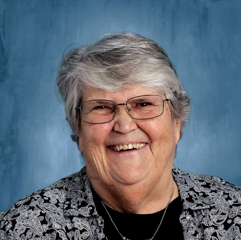 An older gray haired woman in professional attire smiles