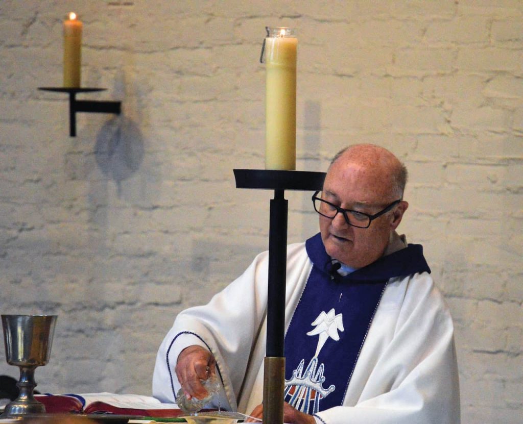 A balding Catholic priest prepares to celebrate Mass