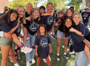 Smiling elementary and high school students gather together outdoors in summer