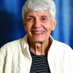 An older woman with short gray and white hair smiles