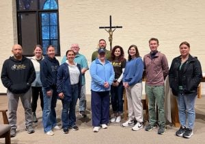 A group of several teachers on a retreat in a chapel standing and smiling together.