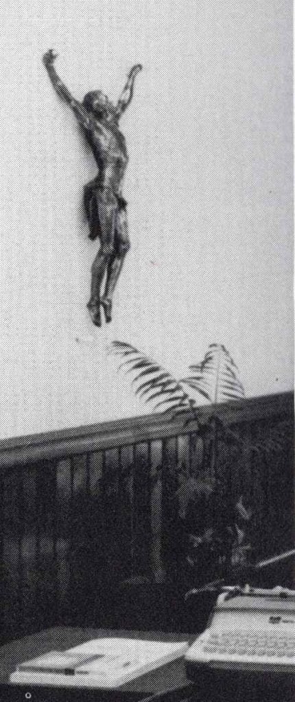 Archival scan of a photo printed in the Loretto Magazine. A statue of the crucified Christ hangs over a desk.