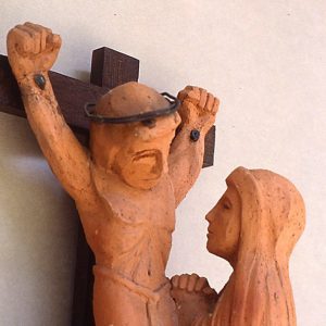 Sculpture of Jesus on the cross with a woman praying before him.