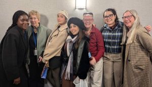 A group of women of diverse ages and backgrounds pose for a quirky group photo.