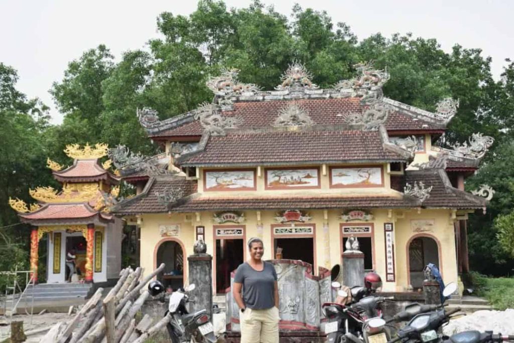 A woman stands in front of an intricately designed temple in Vietnam