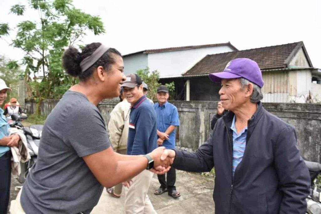 A woman and man smile and shake hands as they meet for the first time in a small village in Vietnam.