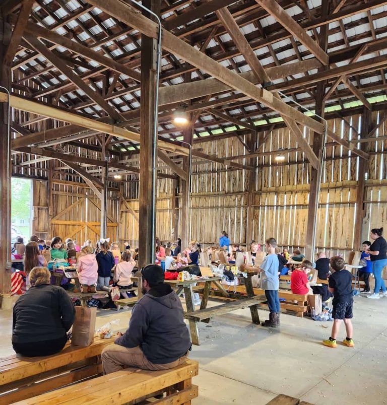 A group of people sitting at wooden tables in a restored wooden barn.