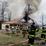 Burning house and firefighters gathered in front