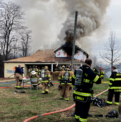 Burning house and firefighters gathered in front