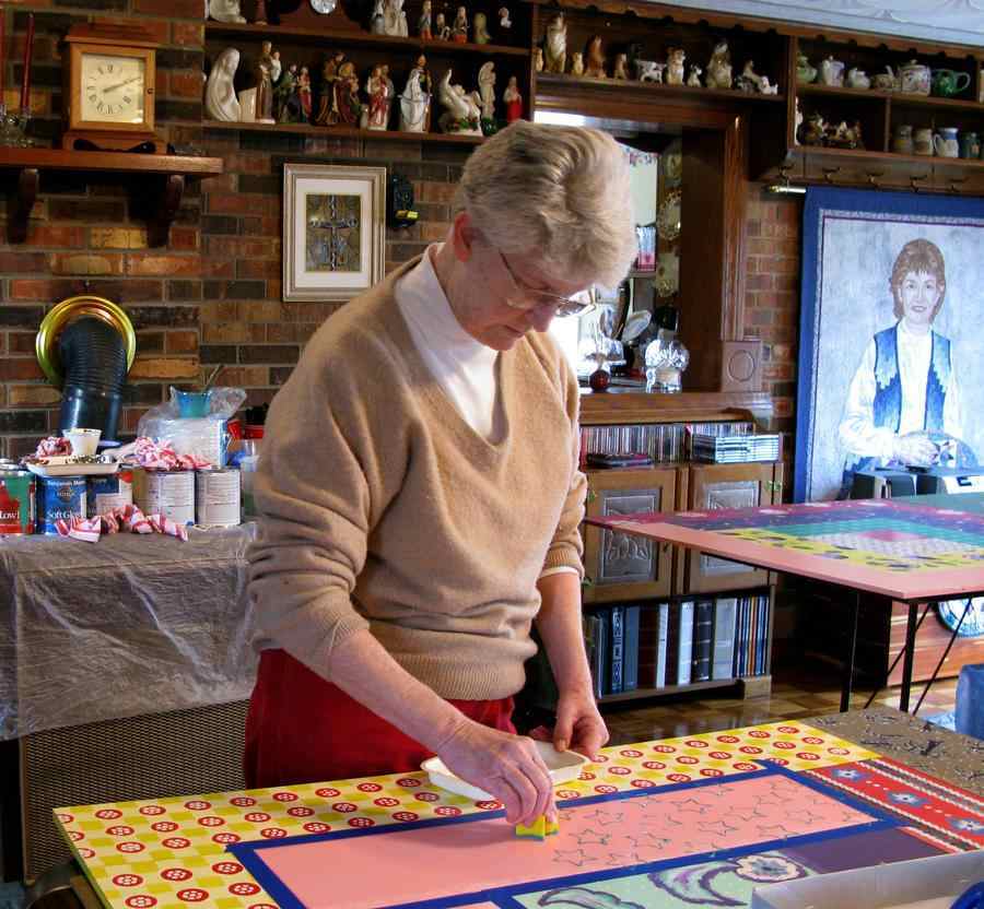 A woman sponge-paints a design as a quilt section.