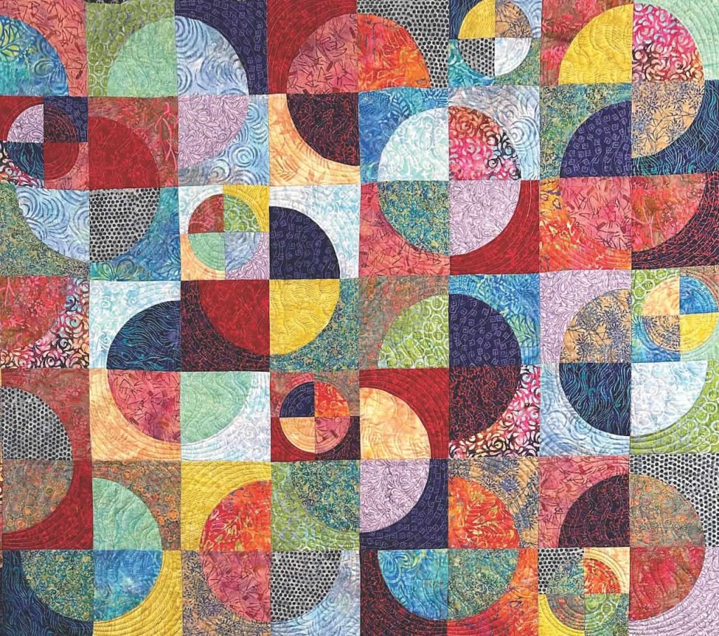 A colorful rainbow colored intricately patterned quilt with overlapping circles titled "Circle Dance"
