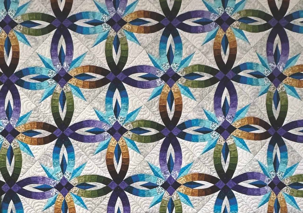 a star patterned quilt of blue, green, purple, white and yellow