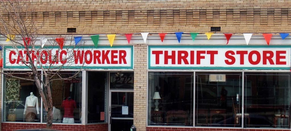 The front of a thrift store. A brick building that says "Catholic Worker Thrift Store" in big red letters.