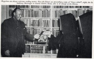 Archival news clipping of a photo of two nuns in habits handing a magazine to a Black man in a suit standing in front of a wall of bookshelves. The caption across the top reads "Magazines are always welcome reading matter. Here the Sisters are presenting a copy of 'Guess what?', right, the St. Anthony Messenger to Guard Charles Head, who is in charge of the library.