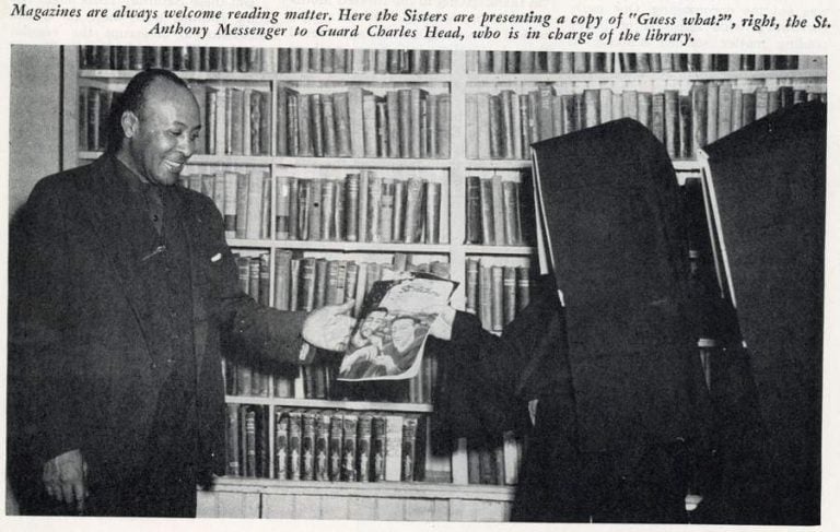 Archival news clipping of a photo of two nuns in habits handing a magazine to a Black man in a suit standing in front of a wall of bookshelves. The caption across the top reads "Magazines are always welcome reading matter. Here the Sisters are presenting a copy of 'Guess what?', right, the St. Anthony Messenger to Guard Charles Head, who is in charge of the library.