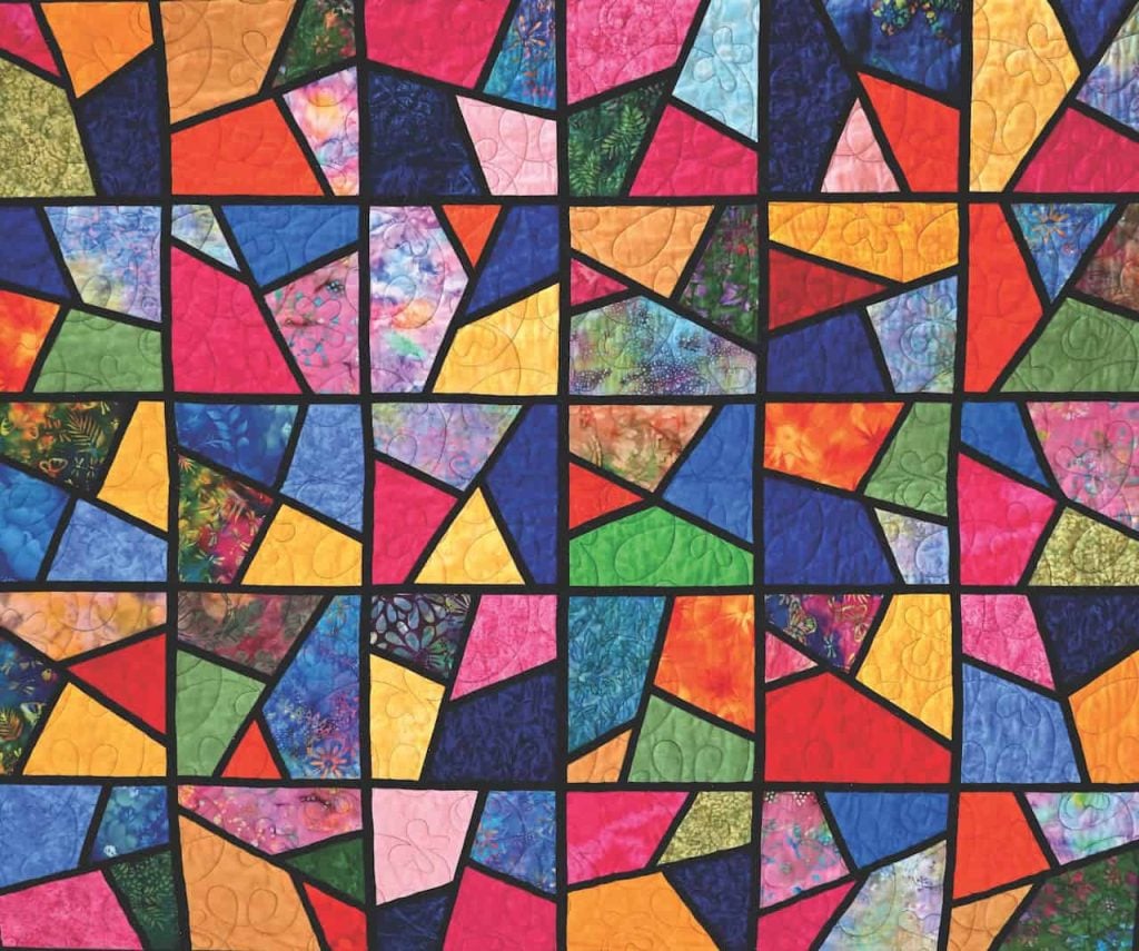 A quilt that mimics colorful stained glass in all colors of the rainbow.