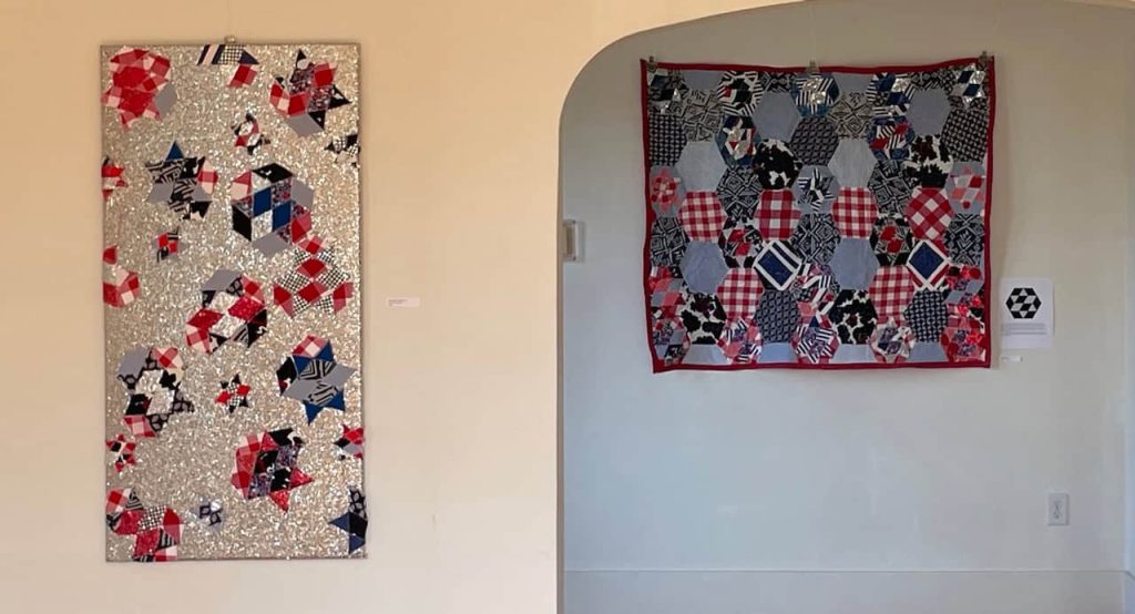Two quilted pieces of art hung up in a gallery space.