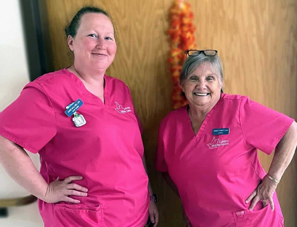 Two nurses smiling together in bright pink scrubs