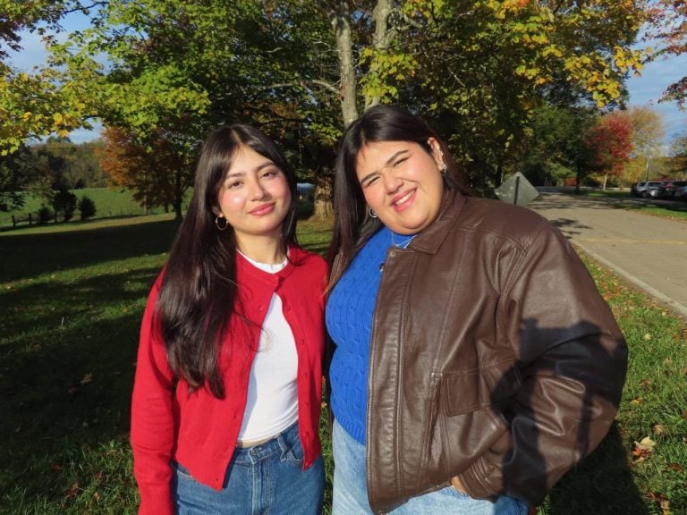 Two young Latina women smiling for a photo outside.