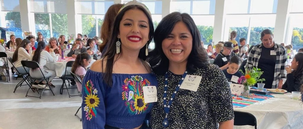 A teacher takes a photo with a student who is wearing an Mexican-style embroidered blouse on the school's annual Latino Heritage Night.