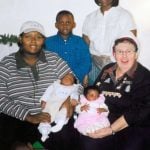 A nuns in a Santa hat celebrates Christmas with a family. A mother and her five children.