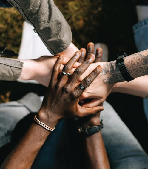 Hands of people of different races clasped together in a circle.