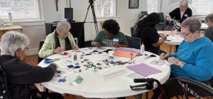 Older residents at the Loretto Motherhouse in Kentucky sitting around a table with a West End Women's Collaborative member creating a collage.