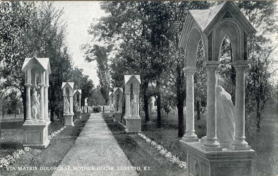 A black-and-white postcard looking down the walk leading into the Loretto Motherhouse Cemetery with the stations of the Seven Dolors along the way. Text at the bottom of the postcard reads "Via Matris Dolorosae Mother House. Loretto. KY."