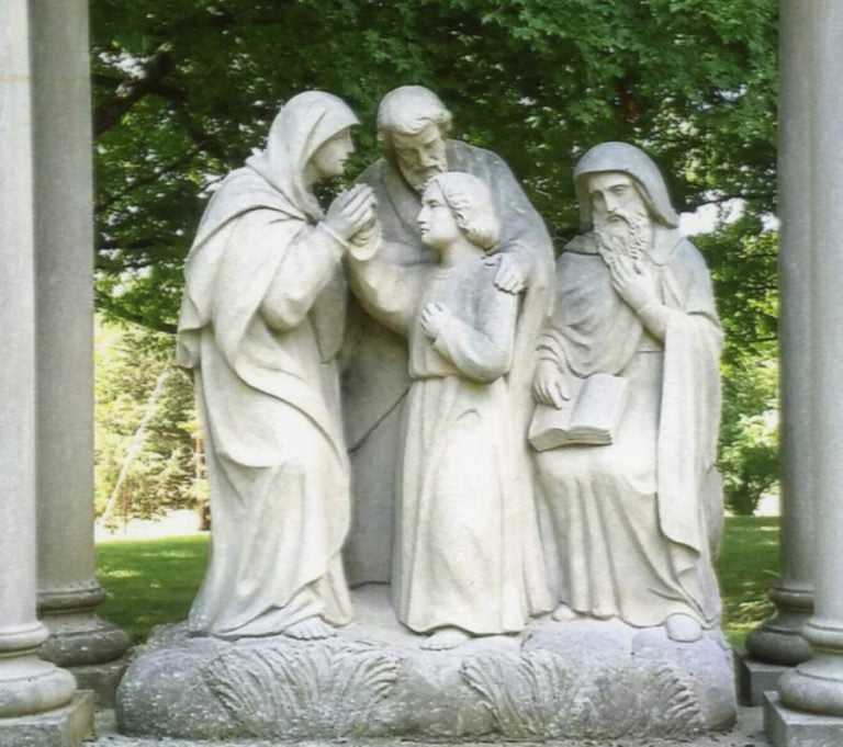 A marble sculpture of the child Jesus being found by his parents after being lost in the temple. A scholar is also depicted in the scene, seated to the right with a book on his lap.