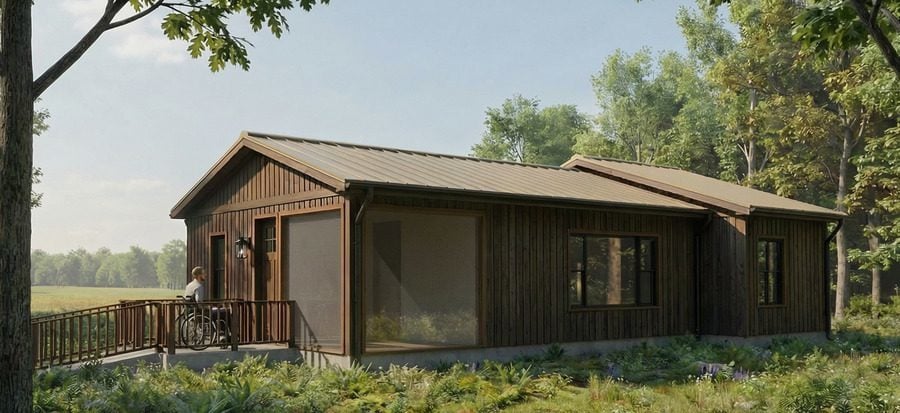 Rendering of a fully accessible cabin in the woods with man in a wheelchair approaching the front door via the ramp.