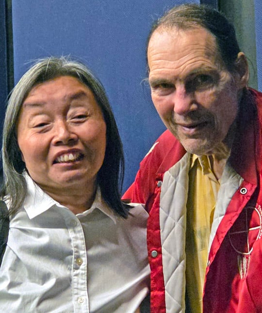 A middle-aged Asian woman stands beside an older white man.